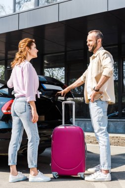 araba ve pembe bagaj yanında dururken mutlu kadın bakarak yakışıklı ve neşeli adam 