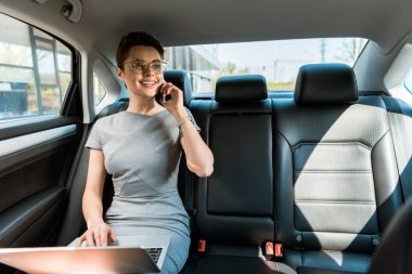 arabada dizüstü bilgisayar kullanırken akıllı telefon konuşurken gözlük mutlu iş kadını 