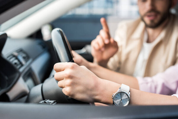 cropped view of woman driving car near man pointing with finger 