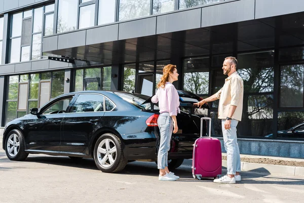 Cheerful Man Looking Happy Woman While Standing Car Pink Luggage — Stock Photo, Image