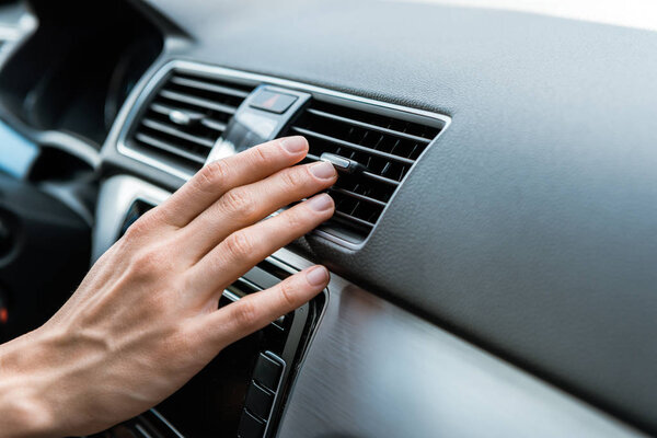 cropped view of man touching air conditioner switch in car 