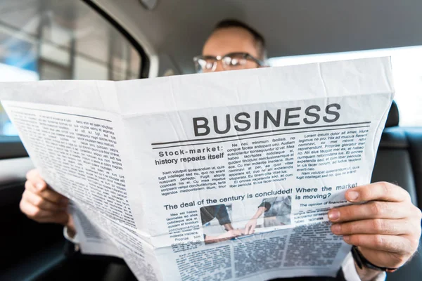 selective focus of man reading business newspaper in car