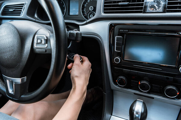 cropped view of woman putting car key in keyhole while sitting in car 