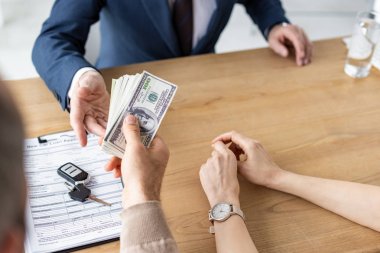 kadın yakınındaki araba satıcısına dolar banknotlar veren adam kırpılmış görünümü 