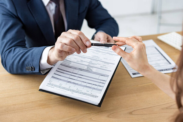 обрезанный вид автодилера, дающего перо женщине во время хранения буфера обмена с документом
 