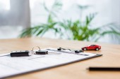 selective focus of  car key on clipboard with document near pen and toy car 