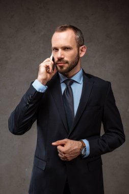 gri üzerinde dururken akıllı telefonda konuşurken yakışıklı işadamı 