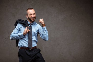 gri üzerinde kutlama yaparken takım elbise neşeli işadamı gesturing 
