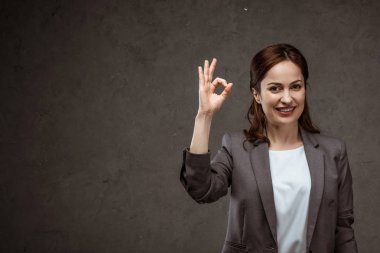 neşeli esmer kadın ok işareti gösteren ve gri üzerinde gülümseyen 