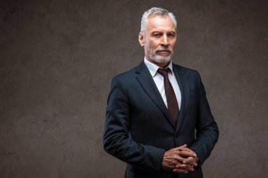 gri üzerinde sıkıştırılmış elleri ile ayakta takım elbise başarılı işadamı 