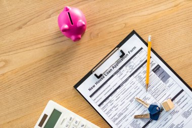 anahtarlar, kalem, pembe kumbara ve hesap makinesi yakın belge üzerinde yeni ev kredisi başvuru formu ile pano üst görünümü 