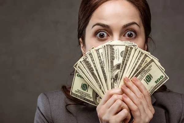 Surprised Brunette Businesswoman Covering Face Dollar Banknotes Grey — Stock Photo, Image