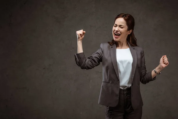 兴奋的黑发女人庆祝胜利 而站在灰色 — 图库照片