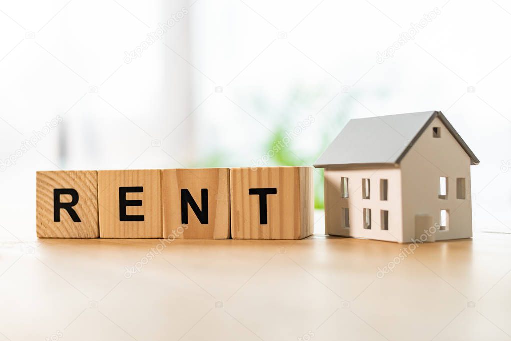 house model near cubes with rent lettering on wooden table