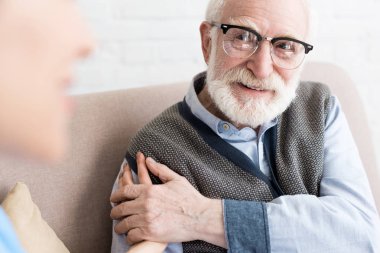 Selective focus of glad elderly man looking at nurse clipart
