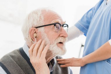 Profile of happy bearded man with hearing aid, looking away clipart