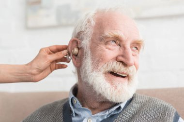 Happy grey haired man with hearing aid, and looking away clipart