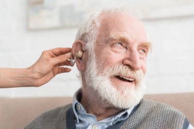 Happy grey haired man with hearing aid, and looking away clipart