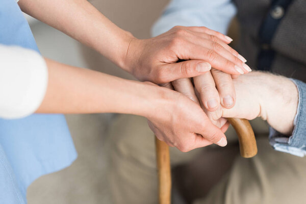 Cropped view of woman holding hands with senior man