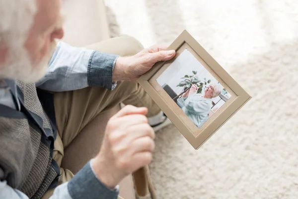 Rentner Sitzt Auf Couch Und Hält Fotorahmen Der Hand — Stockfoto