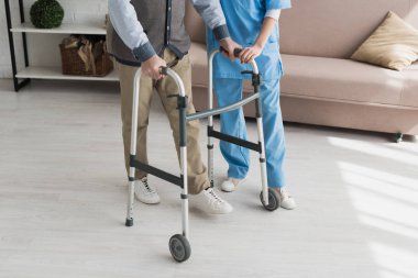 Senior man walking with nurse, and recovering from injury