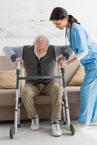 Nurse Helping Retired Man Getting Sofa — Stock Photo, Image