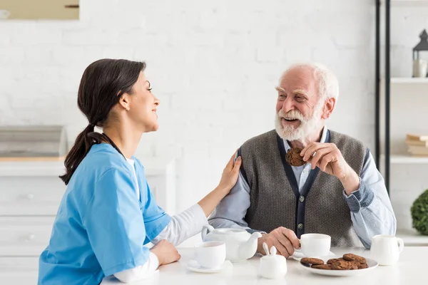 Krankenschwester Sitzt Mit Senior Küche Und Legt Hand Auf Seine — Stockfoto