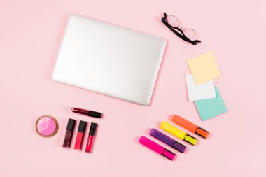 dizüstü bilgisayar, gözlük, vurgulayıcılar ve pembe dekoratif kozmetik üst görünümü