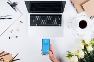 Kiev, Ukrayna - 11 Mayıs 2019: işyerinde ekranda skype uygulaması ile akıllı telefon tutan adamın kırpılmış görünümü