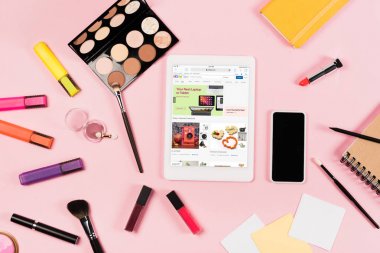 ekranda ebay uygulaması ile dijital tablet üst görünümü, boş ekranlı akıllı telefon, vurgulayıcılar ve pembe dekoratif kozmetik