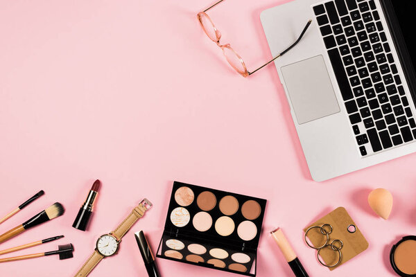 top view of laptop, accessories and decorative cosmetics on pink