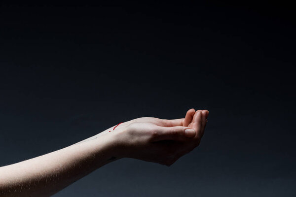 cropped view of woman holding hands up on dark
