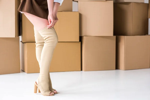 Vista Recortada Niña Pie Tocando Las Botas Cerca Cajas Blanco — Foto de Stock