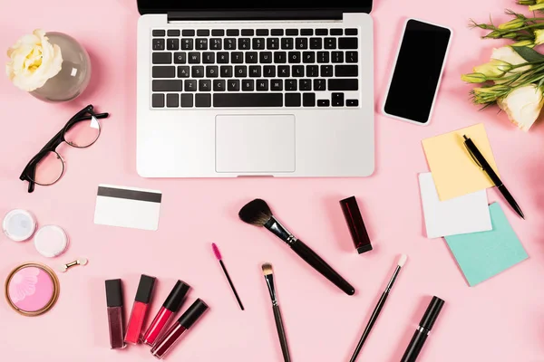 Top view of laptop, smartphone with blank screen, credit card, glasses, flowers and decorative cosmetics on pink — Stock Image Top View Laptop Smartphone Blank Screen Credit Card Glasses Flowers Royalty Free Stock Images