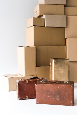 beyaz karton kutular yığını yakınında kahverengi bavul 