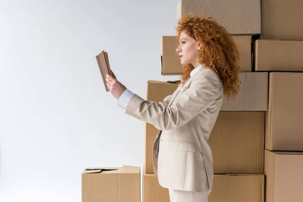 Chica Pelirroja Atractiva Lectura Libro Cerca Cajas Marrones Blanco — Foto de Stock