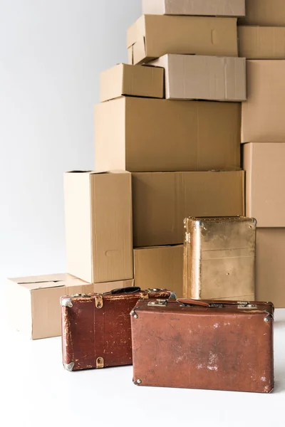 白のカートンボックスのスタックの近くに茶色のスーツケース — ストック写真