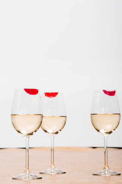 красные отпечатки помады на бокалах для шампанского с алкоголем на белом
 