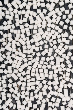 top view of white sugar cubes on black wooden surface  clipart