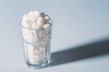 white sugar cubes in glass on grey background with copy space clipart