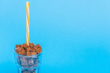 kopya alanı ile mavi izole saman ve kahverengi şeker küpleri ile cam
