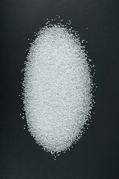top view of sweet white sugar crystals on black background