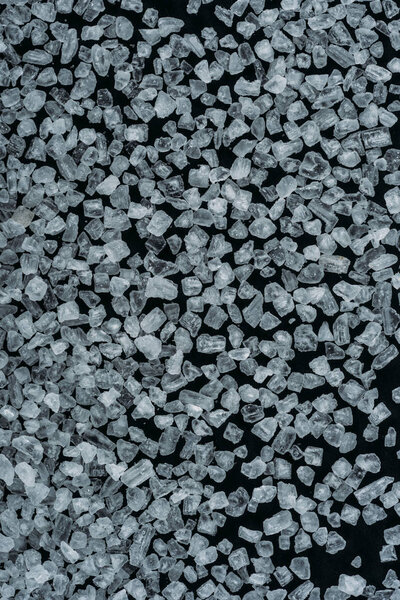 top view of white sweet sugar crystals on black surface