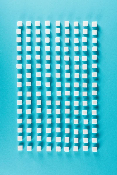 青い表面の列に配置された白砂糖キューブの上のビュー — ストック写真