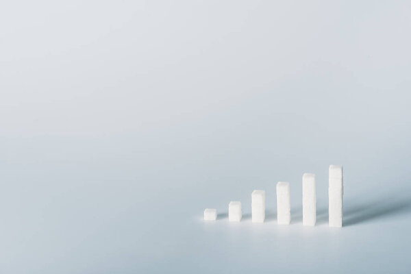 white sugar cubes arranged in stacks on grey background with copy space