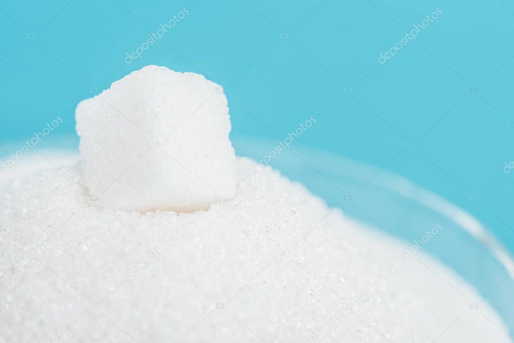 white sugar cube on sugar crystals isolated on blue
