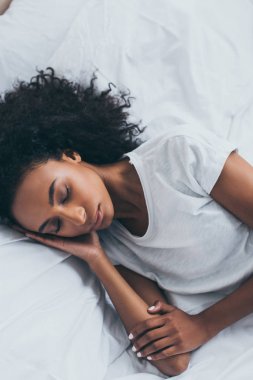 beautiful tired african american woman sleeping on white bedding  clipart