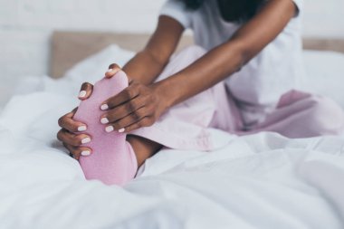 yatak odasında ayak ağrısı muzdarip Afrikalı Amerikalı kadının kırpılmış görünümü