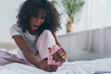 selective focus of young african american woman suffering from foot pain in bedroom clipart