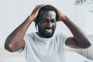 yatak odasında baş ağrısı muzdarip mutsuz afrikalı amerikalı adam